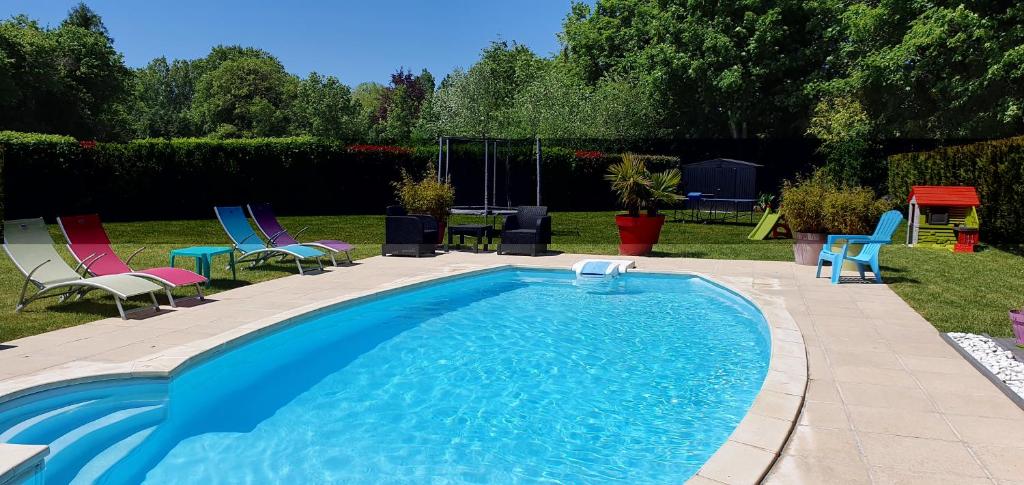 a swimming pool with chairs and a table in a yard at Suite Parentale du Relais de Drugy in Saint-Riquier