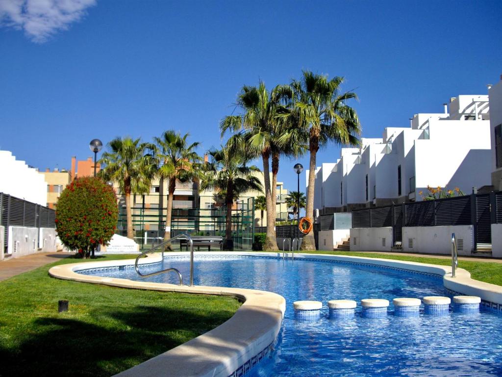 una gran piscina con palmeras y edificios en Residencial Dulcinea - Chalet, en Alcossebre