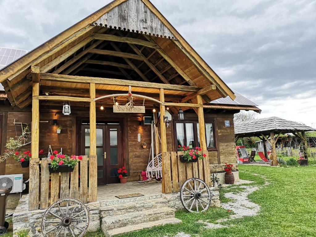 a wooden house with twookedoked wheels in front of it at Naša mala koliba in Vojnić