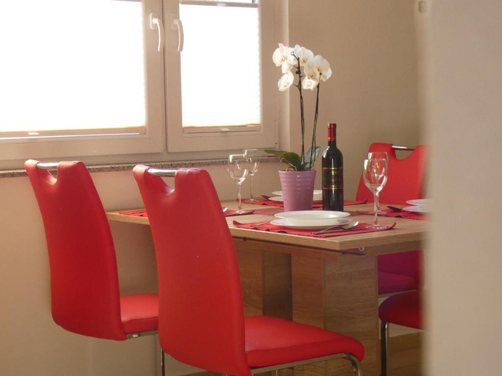 una mesa de comedor con sillas rojas y una botella de vino en Apartment & Olive oil Valuma en Koper