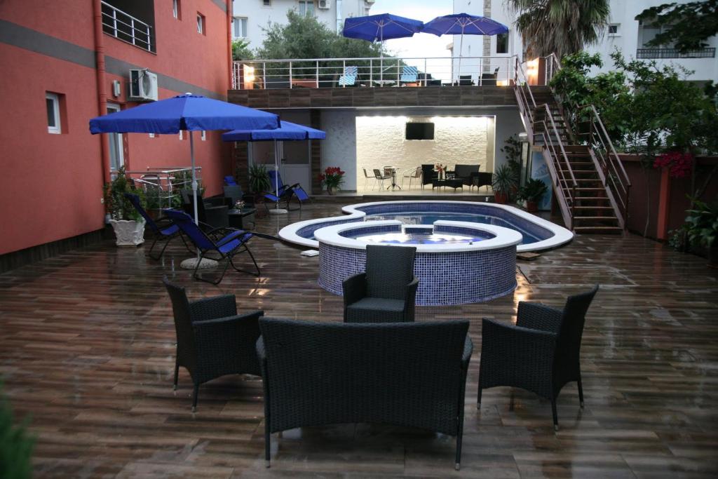 un patio con piscina, sillas y sombrillas en VilaElenaMarko, en Budva