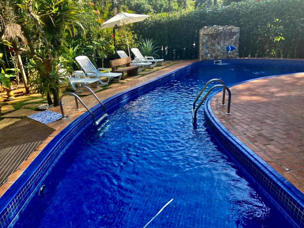 een zwembad met blauw water in een achtertuin bij Suítes Guaratuba in Bertioga