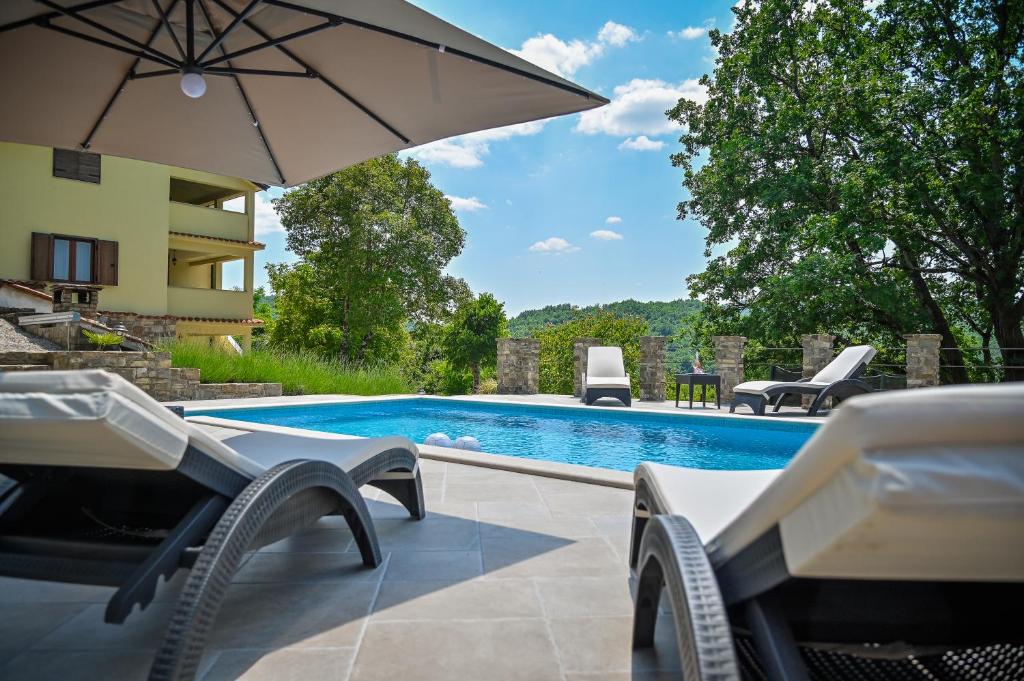 una piscina con sillas y sombrilla en Villa Brbon - Serene Getaway, en Krbune
