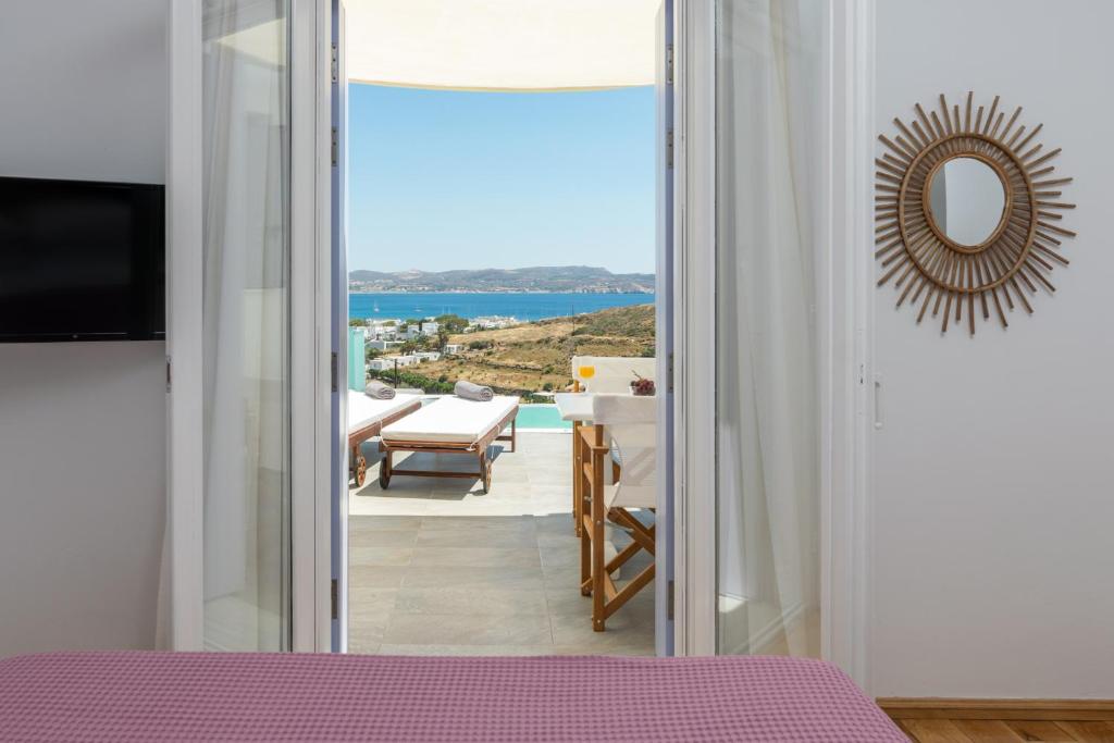 a bedroom with a view of the ocean through a door at Milesian Suites in Adamantas