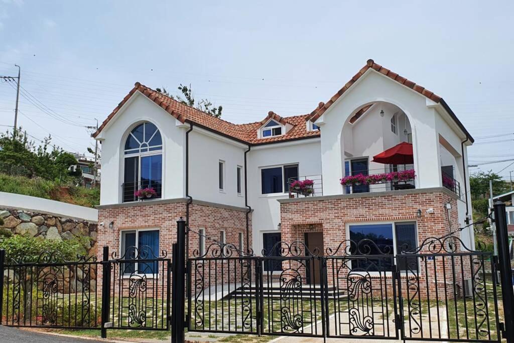 uma grande casa branca com uma cerca preta em High-Quality House Ocean view em Tongyeong