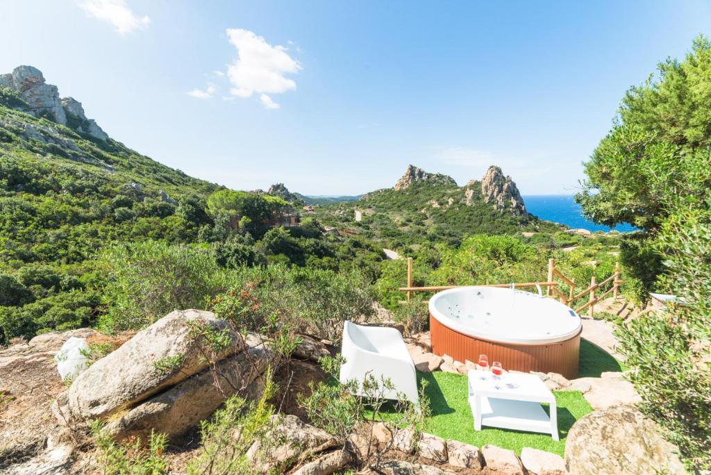 einen Whirlpool und zwei Stühle auf einem Hügel mit dem Meer in der Unterkunft villa aloe 2 in Costa Paradiso