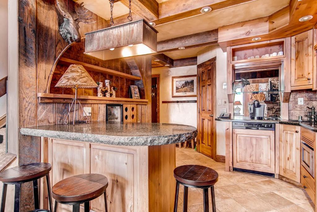 una cocina con armarios de madera y una barra con taburetes en Beaver Run Resort - Peak 9 Penthouse en Breckenridge