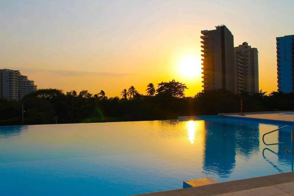 ein großer Pool mit Sonnenuntergang im Hintergrund in der Unterkunft Magnífico apartamento, Santa Marta sector Irotama in Santa Marta