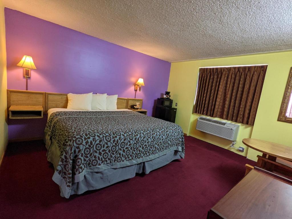a hotel room with a bed and a purple wall at Great Plains Budget Inn in Lincoln
