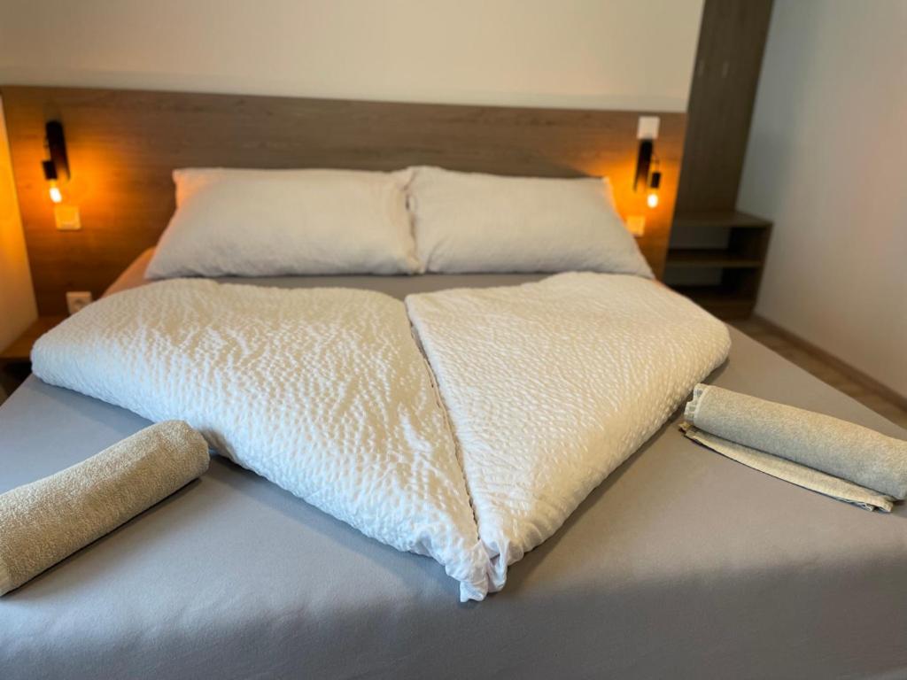 Una cama con sábanas blancas y almohadas. en Kukorica Csárda Apartman en Balatonújlak
