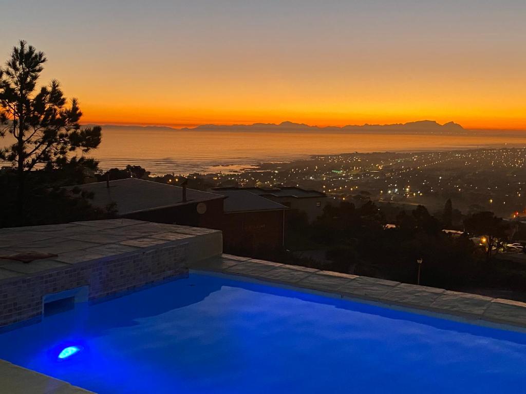 una piscina con puesta de sol en el fondo en On the GBay Villa, en Gordonʼs Bay