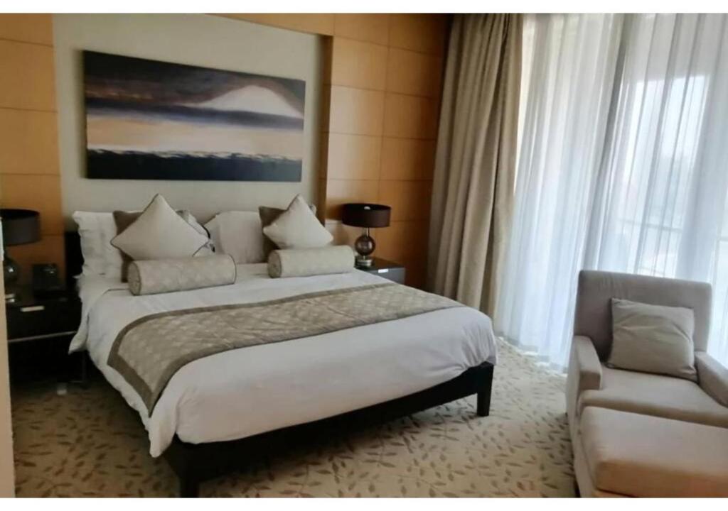 a bedroom with a large bed and a chair at Luxury stay at Dubai Mall Residence Downtown in Dubai