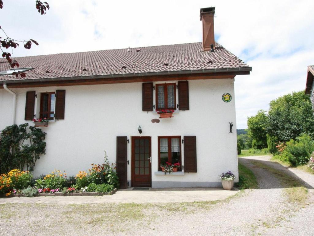 uma casa branca com persianas castanhas e flores em Gîte Le Val-d'Ajol, 5 pièces, 10 personnes - FR-1-589-139 em Le Val-dʼAjol