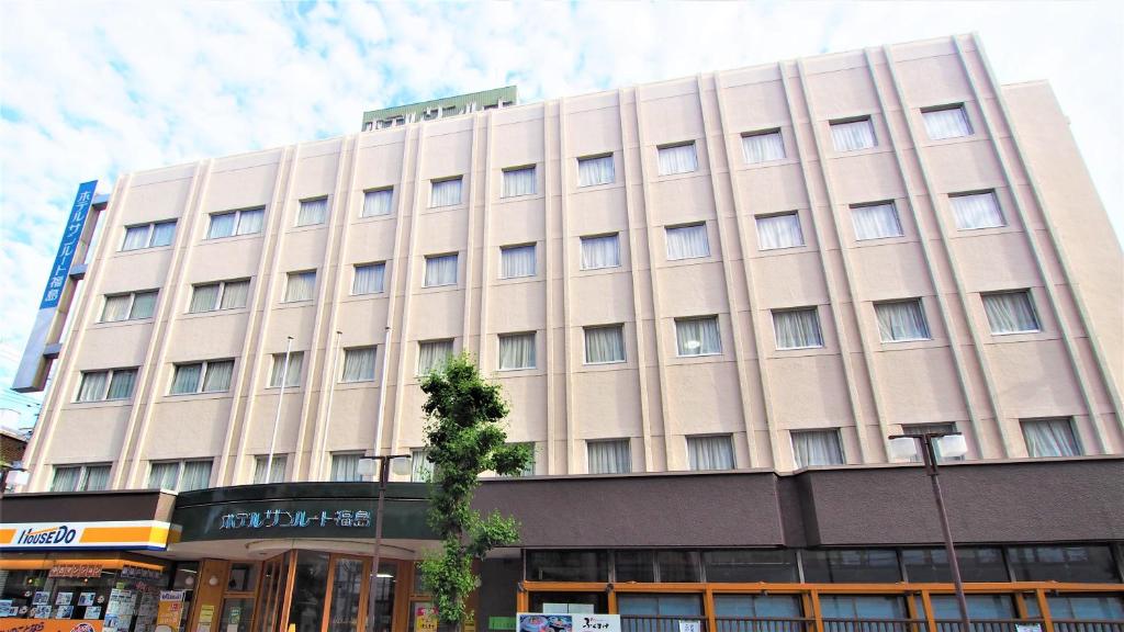 Hotel Sunroute Fukushima في فوكوشيما: مبنى كبير اسمر أمامه شجرة