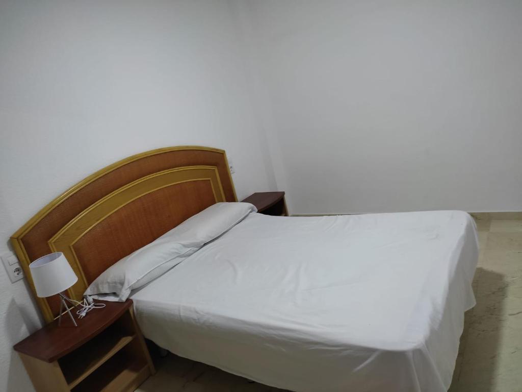 una camera con letto bianco e testiera in legno di garrucha 100 mts playa, 2 Dorm a Garrucha