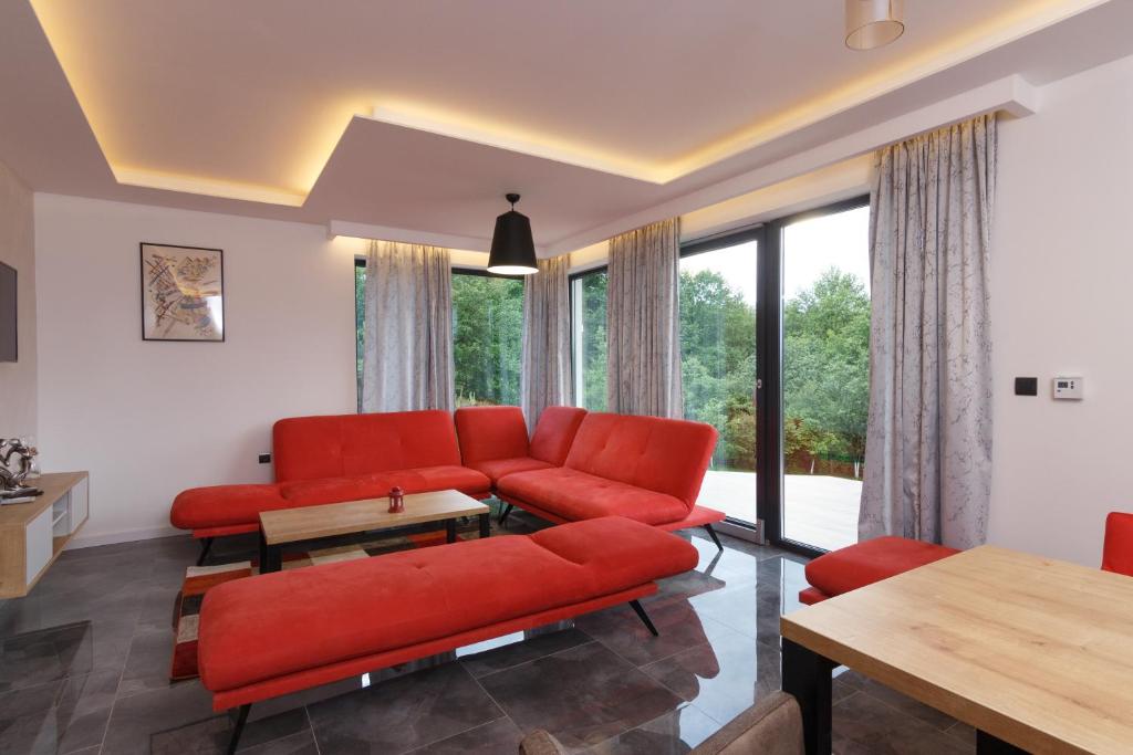 sala de estar con muebles de color rojo y ventanas grandes. en Deluxe Feliciano Apartments, en Visoko