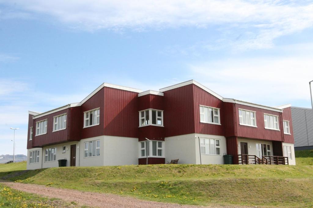 a red and white building on top of a hill at Framtid Hostel in Djúpivogur