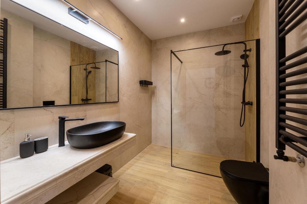 Modern bathroom featuring black oval sink, matte black faucet, walk-in shower with glass partition and wooden floor.