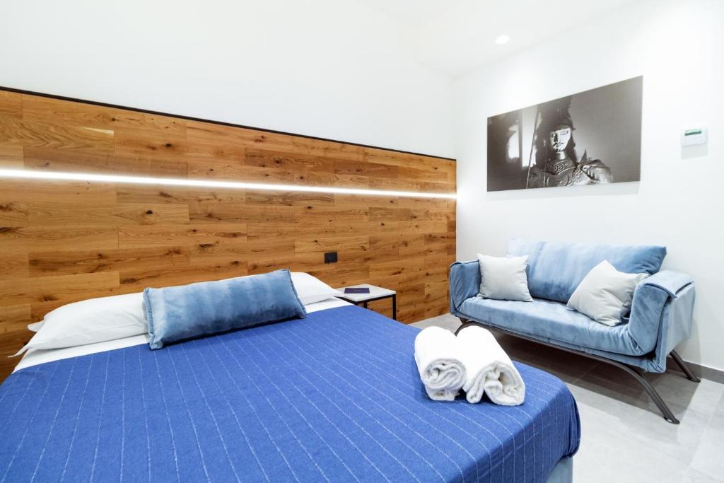 a bedroom with a blue bed and a couch at Hotel Portum in Giardini Naxos