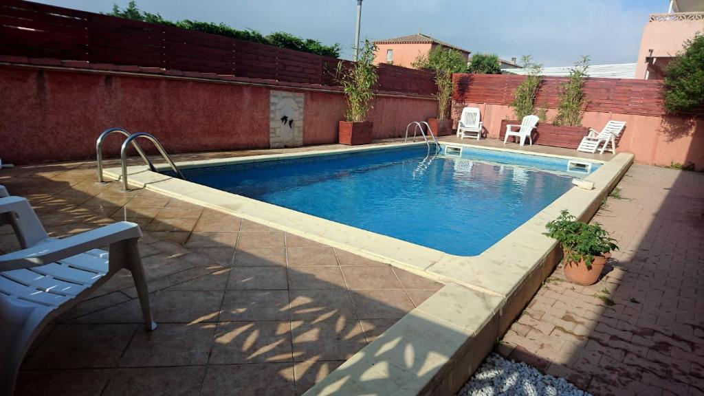 - une piscine avec 2 chaises à côté d'un bâtiment dans l'établissement Appartements dans résidence Avec piscine - Mer à 500m, à Sainte-Marie-la-Mer