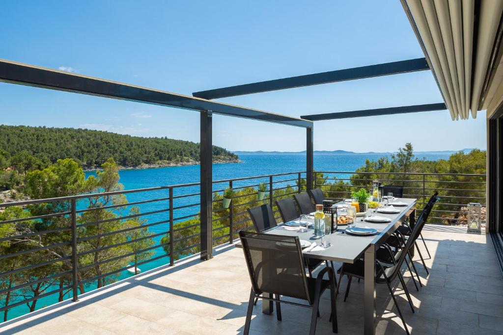 a dining table on a balcony with a view of the water at WATERFRONT SEA DREAM VILLA in Milna