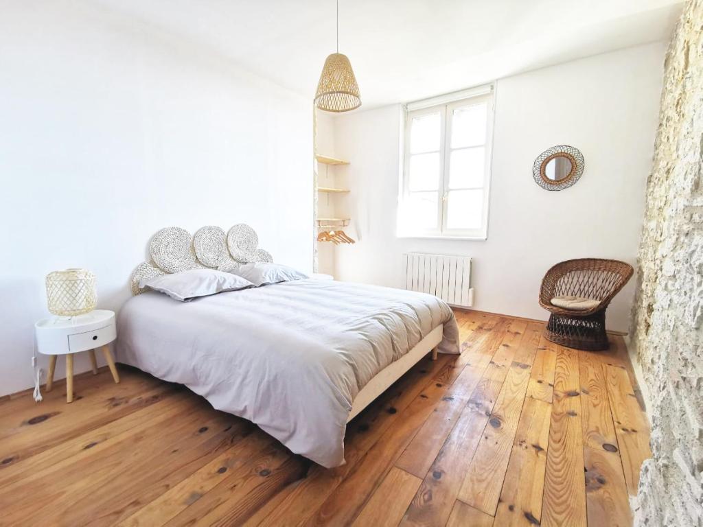 ein Schlafzimmer mit einem großen Bett und Holzboden in der Unterkunft Maison de charme spacieuse, terrasse et vue sur la place in Monflanquin