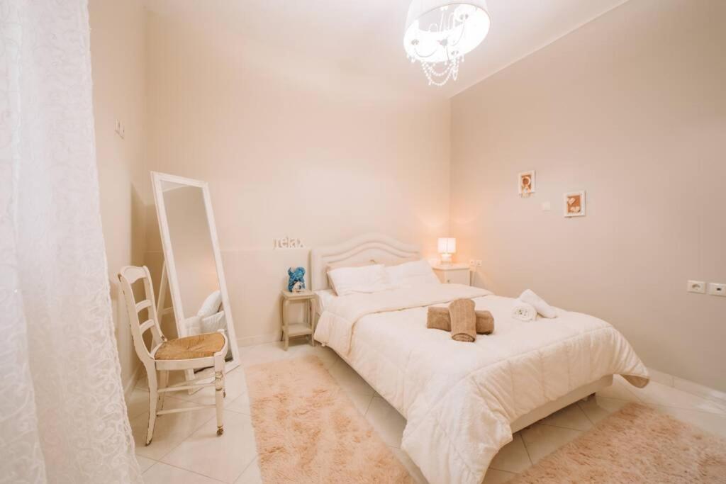 a white bedroom with a bed and a chair at Debbies House in Kalamata