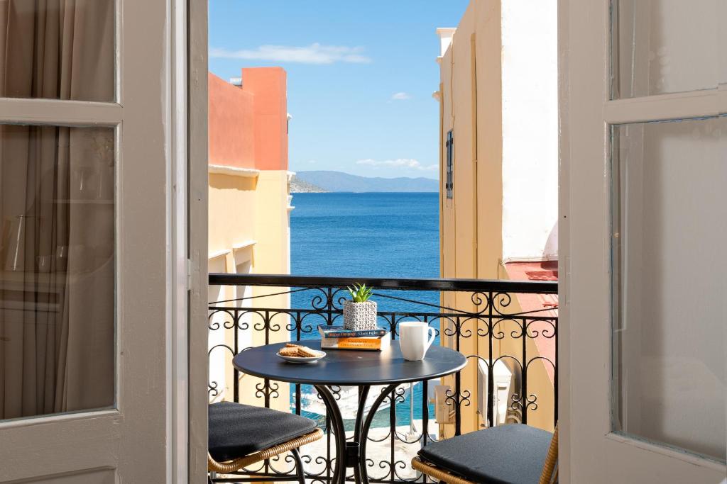einen Balkon mit einem Tisch und Meerblick in der Unterkunft Marika's Deluxe Rooms in Symi