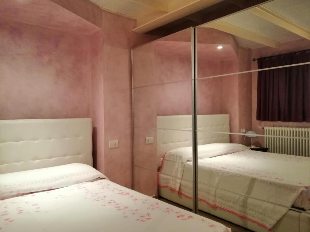 a bedroom with two beds and a mirror at La Casetta di Baveno in Baveno