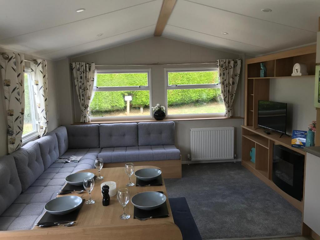 a living room with a couch and a table at Exclusive 3 Bedroom Caravan, Sleeps 8 People at Parkdean Newquay Holiday Park, Cornwall, UK in Newquay Bay Resort