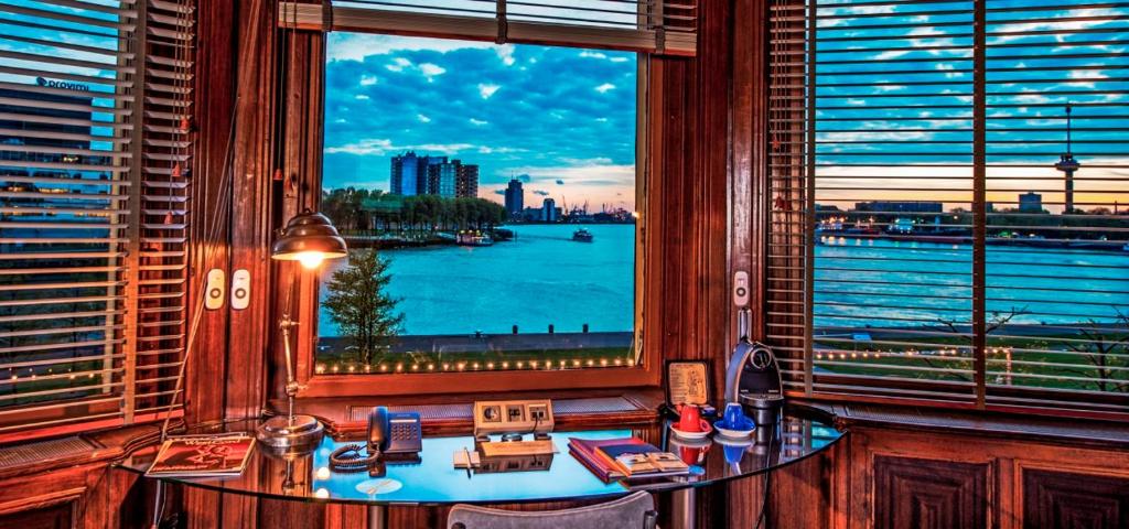 a room with a large window with a view of the water at Hotel New York by WestCord in Rotterdam