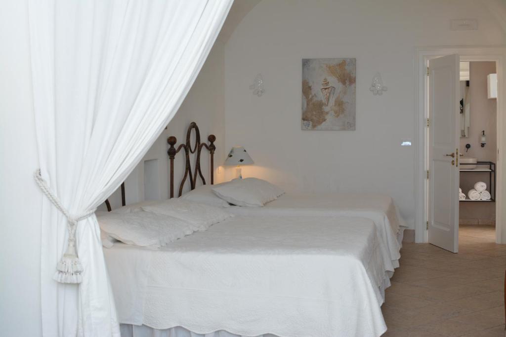 a white bedroom with a bed with white curtains at B&B Palazzo del Capitolo - By I Bastioni San Domenico in Gallipoli