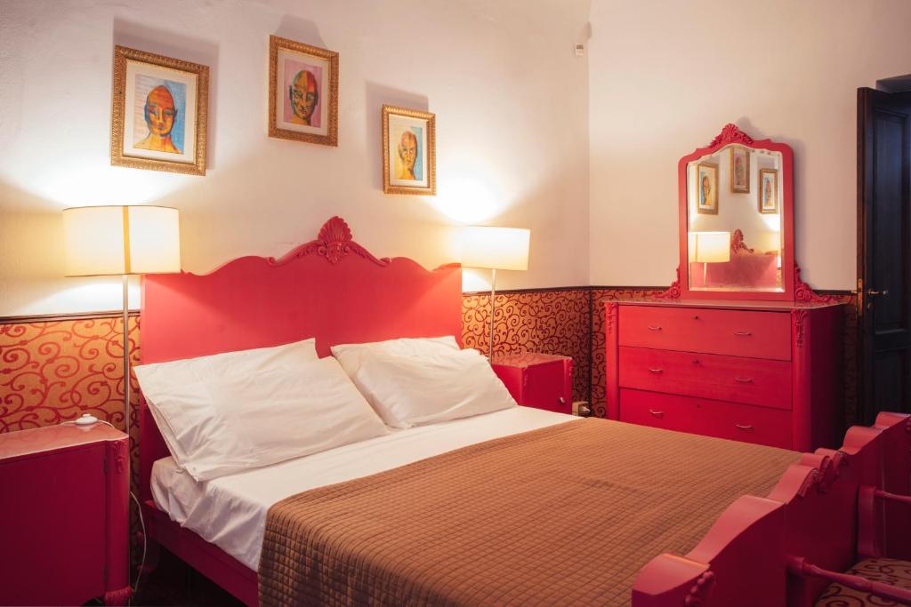um quarto vermelho com uma cama com uma cómoda vermelha e um espelho em Cinematocasa Suite em Palermo