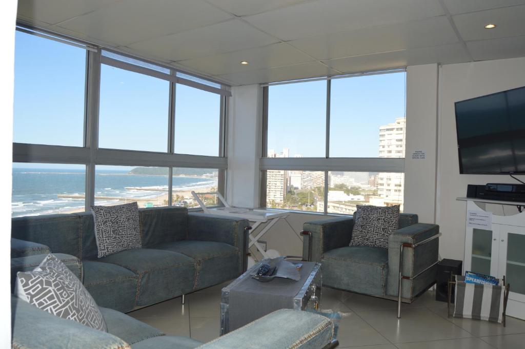 sala de estar con sofás y TV de pantalla plana. en Accommodation Front - Classy 4 Sleeper with Ocean Views en Durban