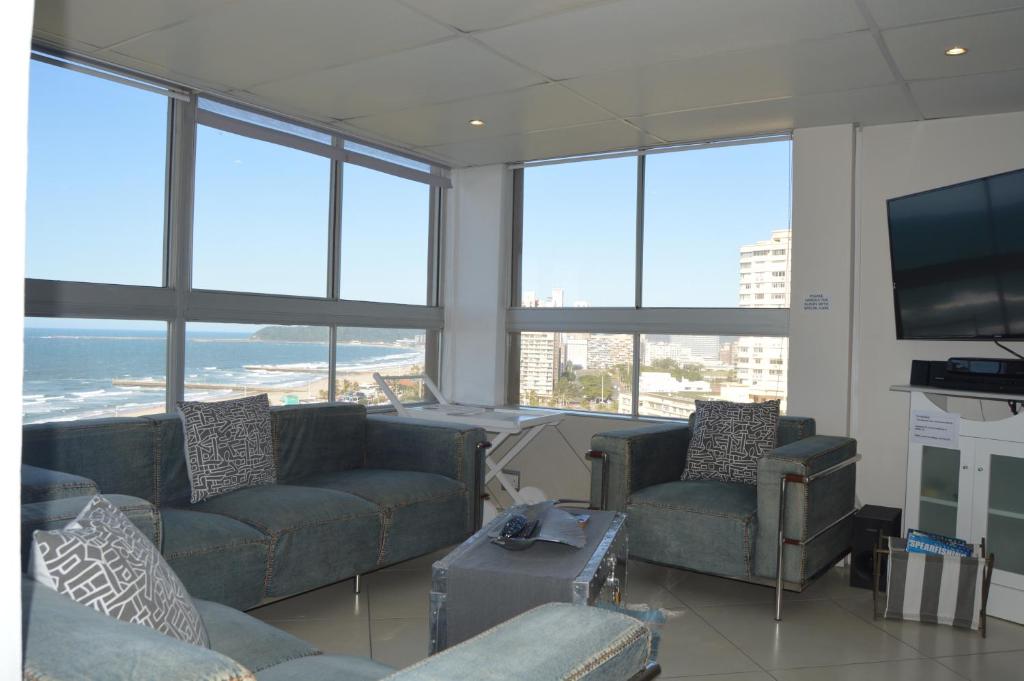 a living room with couches and a flat screen tv at Accommodation Front - Classy 4 Sleeper with Ocean Views in Durban