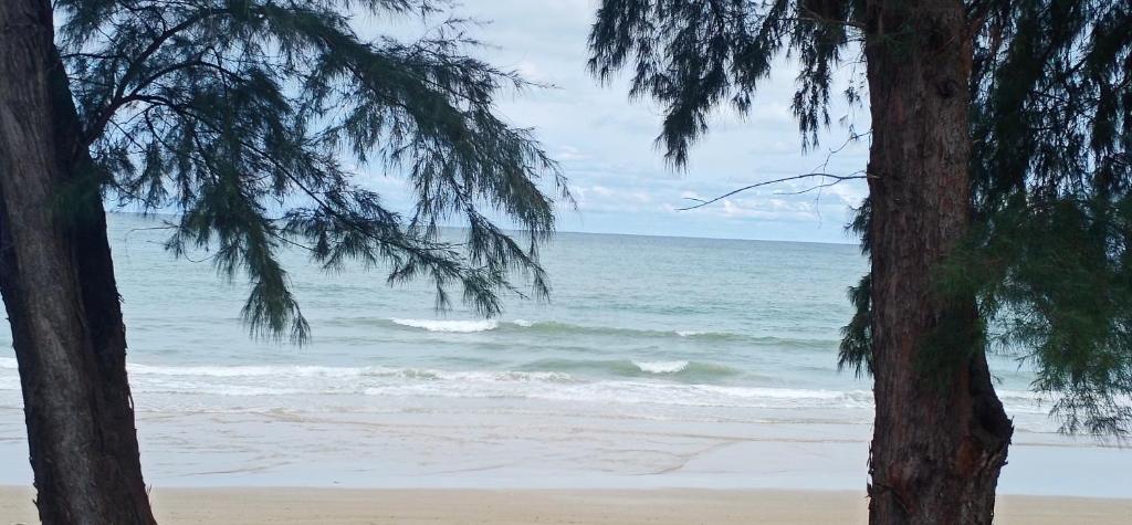 - une vue sur la plage entre deux arbres dans l'établissement Sammy Seaview Mae Ramphueng Beach Frontบ้านช้างทองวิวทะเลหน้าหาดแม่รำพึง, à Rayong