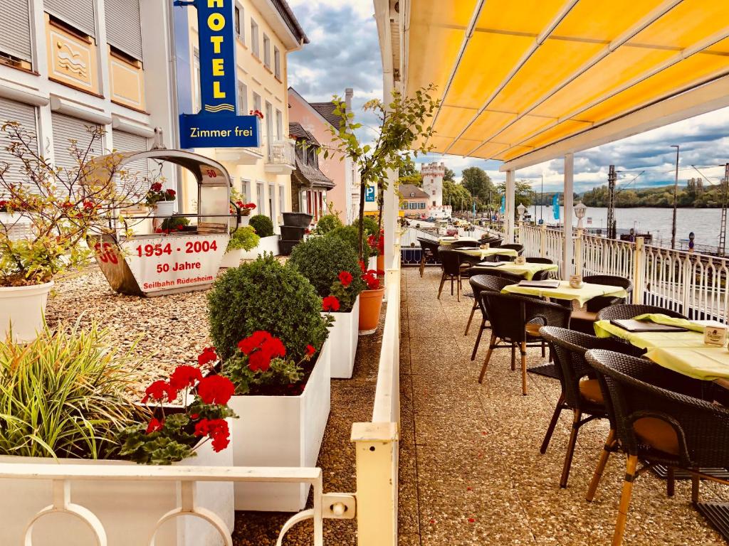 patio restauracji ze stołami, krzesłami i kwiatami w obiekcie Parkhotel Rüdesheim w mieście Rüdesheim am Rhein