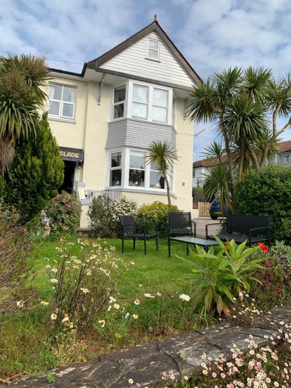 ein Haus mit Stühlen und Palmen im Hof in der Unterkunft San Brelade in Paignton