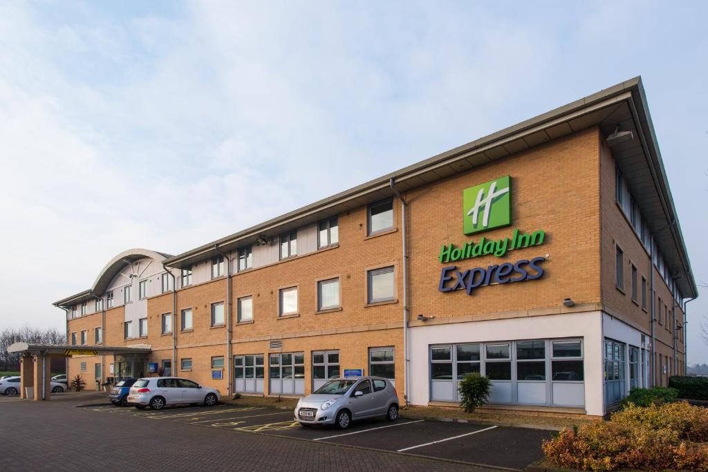 un gran edificio de ladrillo con un signo expreso de felicidad en él en Holiday Inn Express East Midlands Airport, an IHG Hotel, en Castle Donington