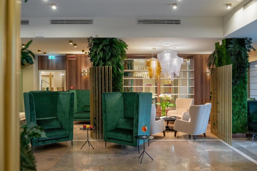 a lobby with green chairs and a table at Hotel Tocq in Milan