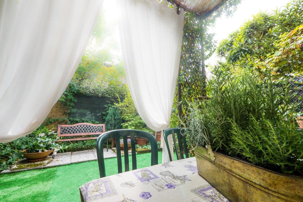 デセンツァーノ・デル・ガルダにあるGarden Sweet House Desenzanoの白いカーテン付きの庭園内のテーブルと椅子