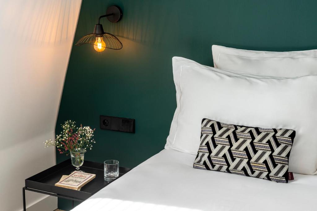 1 cama con almohadas blancas y mesa auxiliar con lámpara en 9Hotel Opera, en París