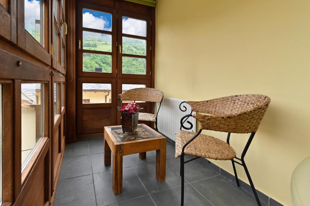 2 sillas y una mesa en una habitación con ventana en Puente del Narcea, en Cangas del Narcea