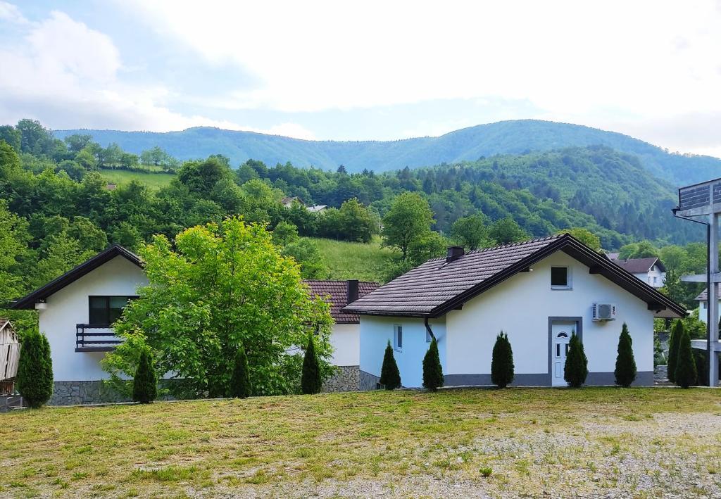 a white house with mountains in the background at Holiday home RIVER NATURE in Jajce