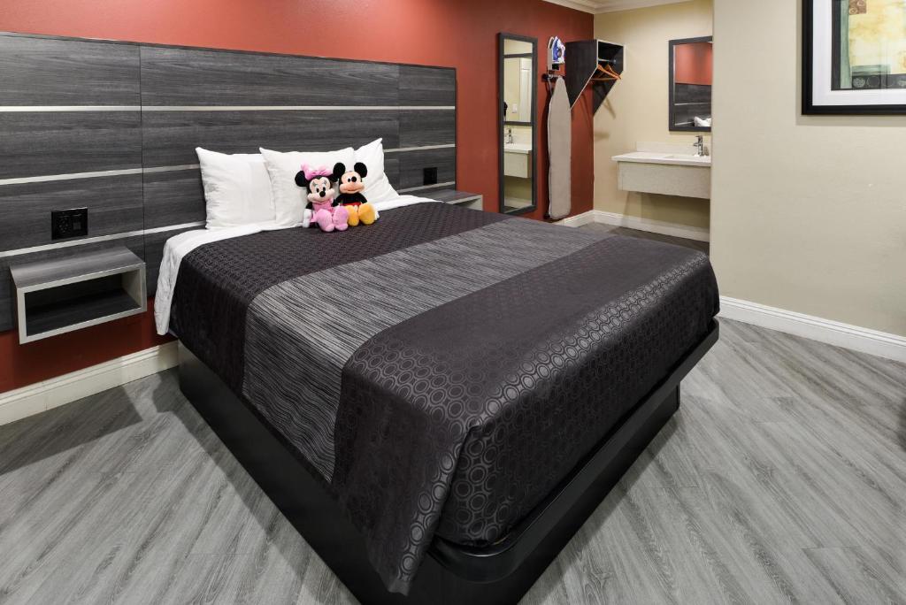 Un dormitorio con una cama grande con dos animales de peluche. en Pacific Inn Anaheim en Anaheim
