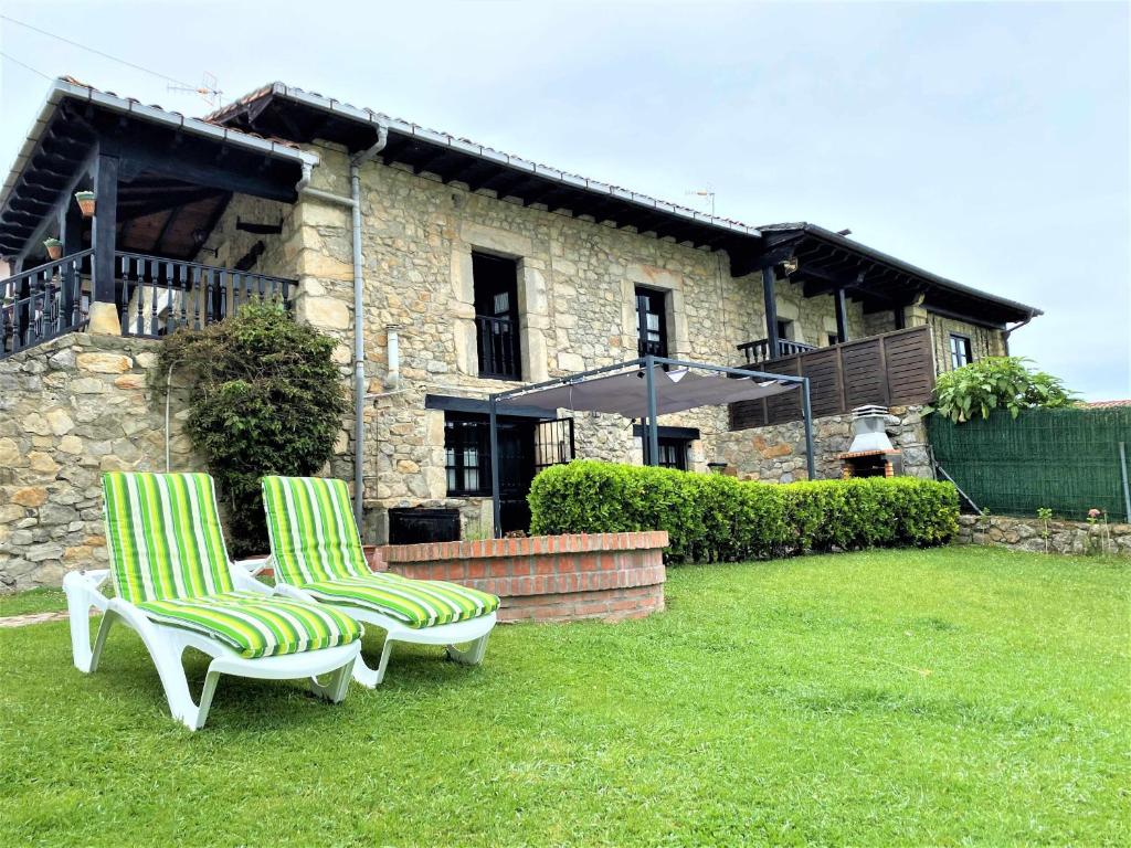 利亞內斯的住宿－Casa Las Hortensias 1 Pendueles，两把椅子和一把伞在房子前面
