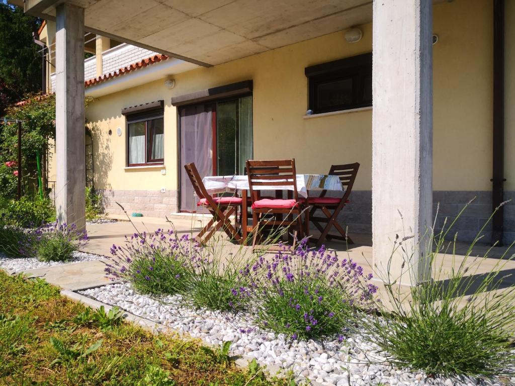 a table and chairs on a porch with purple flowers at Solmar, Apartment with big terrace near nature in Portorož
