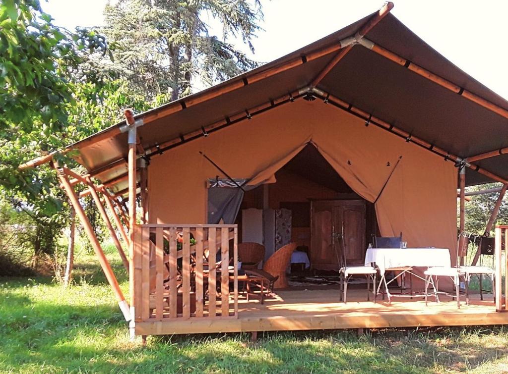 a tent with a table and chairs in a field at Le Lodge de Loge & Broc in La Possonnière