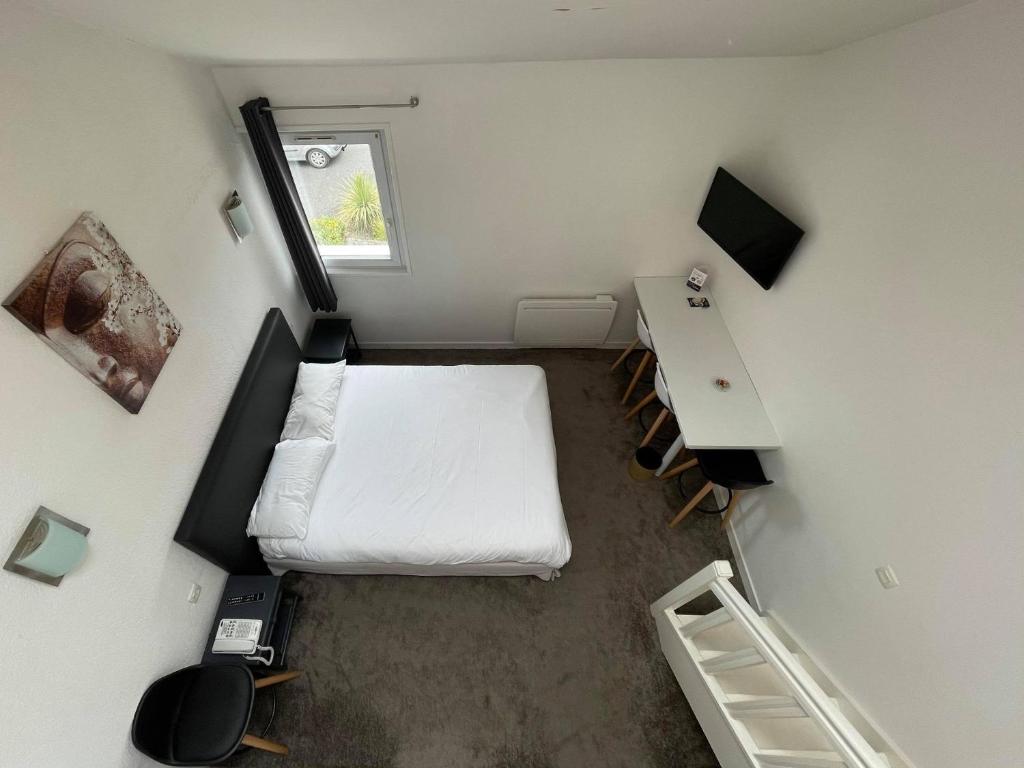 a small room with a white bed and a desk at Hôtel Arcadia in Lannion