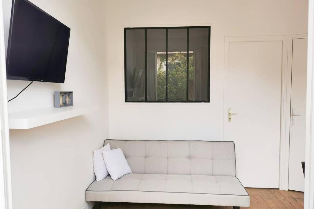 a living room with a white couch and a tv at Joli appartement à 2 pas de Paris in Bagnolet